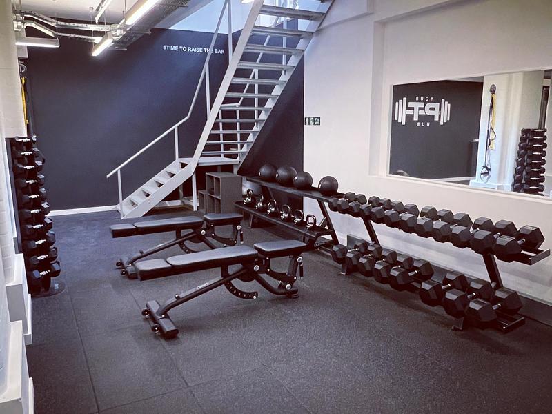 Dumbbell and kettlebell racks beside the studio's mezzanine staircase